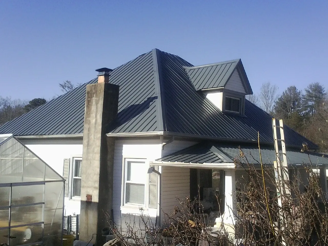 Dark blue standing seam metal roof on a white farmhouse with dormer — Slate & Tile Roof Repair by Roofing Brothers in Wytheville