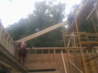Carpenter raising a rafter beam on a new second story frame in Wytheville