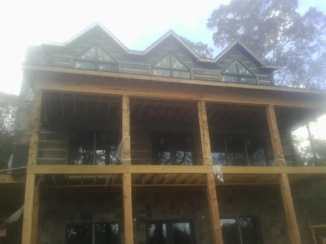 Dormers and porch framing on a large log home under construction — Roof Coating work by our crew in Wytheville