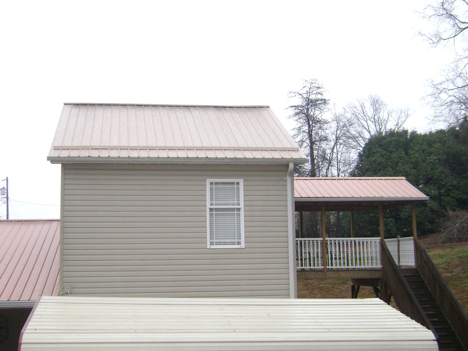 Tan metal roofs on a two story addition and attached porch, from a Roof Replacement job in Wytheville