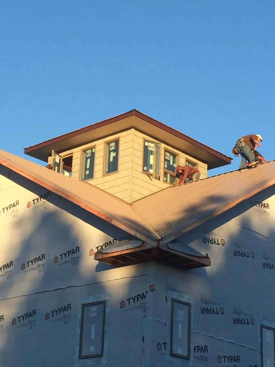 Roofers working around a rooftop cupola on a new metal roof at sunset — Roof Waterproofing in Wytheville by Roofing Brothers